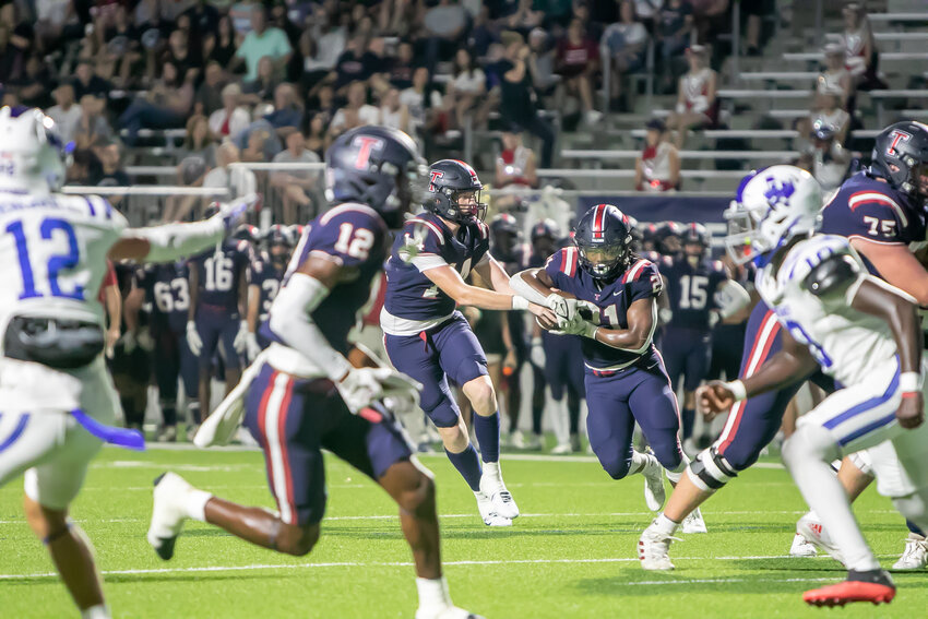 Justin Thierheimer hands the ball off to Caleb Blocker during Thursday's game between Tompkins and Taylor at Legacy Stadium.