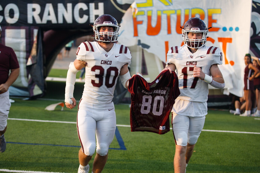 Zack Millen and Noah Matthews carry the jersey of their teammate, who was killed by a vehicle while riding a bike to school on Thursday.