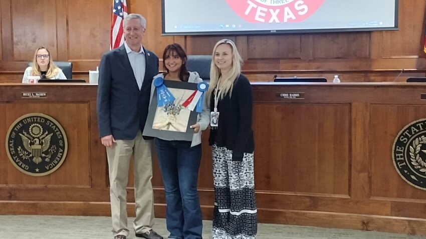 Katy Mayor Dusty Thiele (left) and Ashley Lipsman, City of Katy tourism and marketing event coordinator (right), recognize Mariam Elsherbiny (center) as the winner of the 2023 Katy Rice Harvest Festival art contest &ldquo;Best of Show&rdquo; for her art piece &ldquo;Wildflowers.&rdquo;