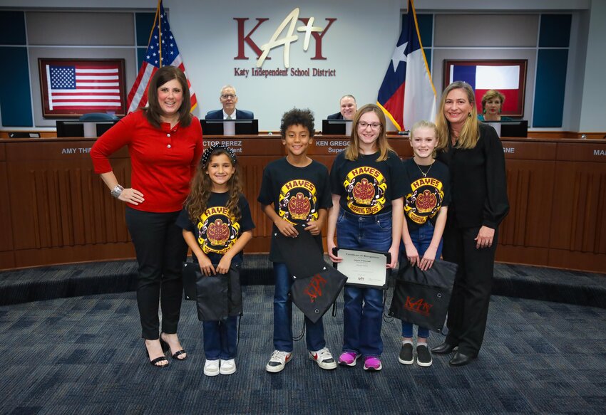 Board Vice President Amy Thieme (left) stands with members of the Hayes Elementary Choir who performed the National Anthem. Music director Kim Peterson is on the right.