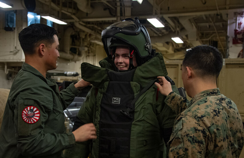 PACIFIC OCEAN (Feb. 17, 2024) Culinary Specialist 2nd Class Nathan Bouchard, center, from Katy, Texas, assigned to the forward-deployed amphibious assault carrier USS America (LHA 6), tries on a bomb suit during an Explosive Ordnance Disposal (EOD) demonstration in the ship&rsquo;s vehicle storage area, during routine operations in the Pacific Ocean, February 17. America, lead ship of the America Amphibious Ready Group, is operating in the U.S. 7th Fleet area of operations. U.S. 7th Fleet is the U.S. Navy&rsquo;s largest forward-deployed numbered fleet, and routinely interacts and operates with allies and partners in preserving a free and open Indo-Pacific region. (U.S. Navy photo by Mass Communication Specialist Seaman Darian Lord)