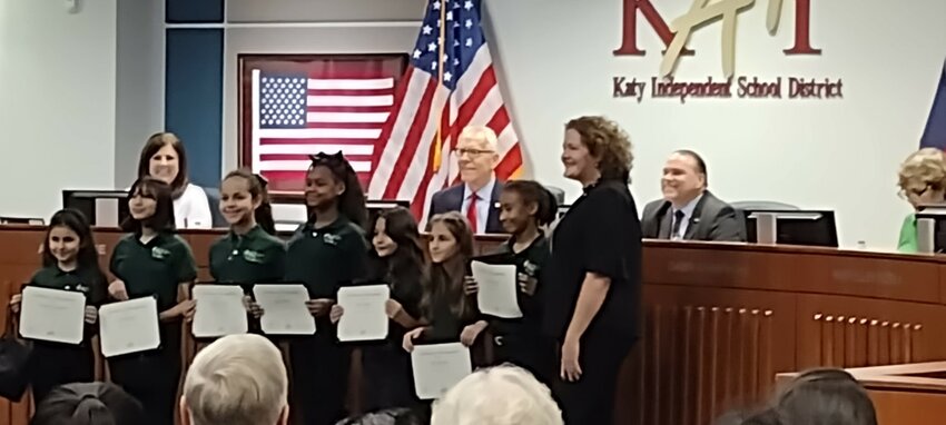 Board member Mary Ellen Cuzela (far right) presents certificates of recognition to members of the Mayde Creek Elementary Choir after their performance of the national anthem.