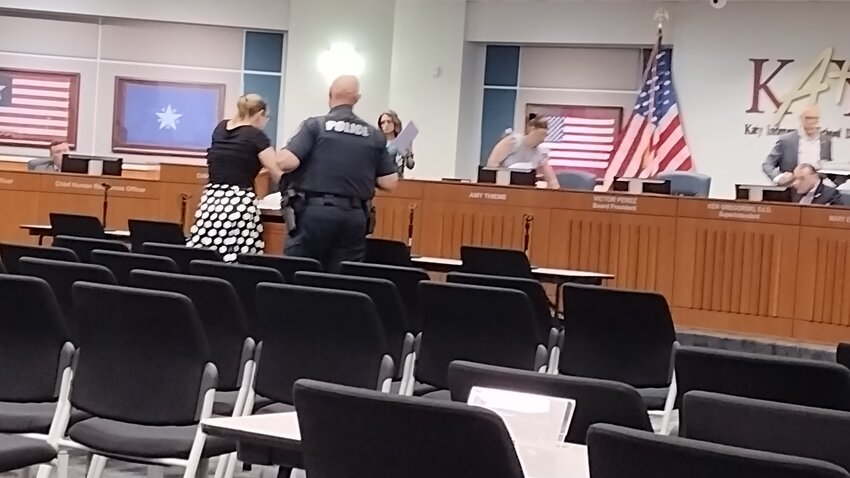 Lisa Lister-Browne (left) is approached by a Katy ISD security officer after she was asked to stop speaking during the public comments portion of Monday night's school board meeting. Board president Victor Perez told Lister-Browne that, while she had signed up to speak on the budget, she was off topic and instructed that her microphone be turned off. Board members (left to right) Morgan Calhoun, board Vice President Amy Thieme and board President Perez are shown leaving the dais to go into closed session; Superintendent Ken Gregorski remains seated on the dais.