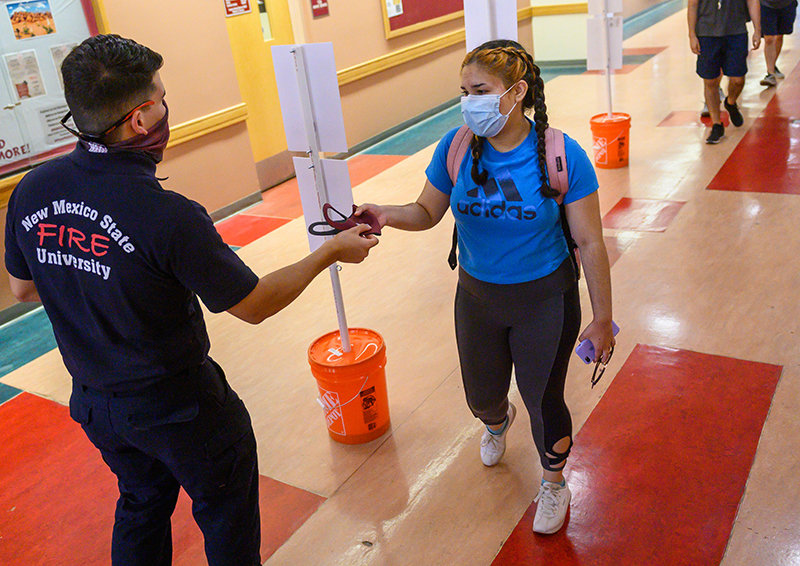 A firefighter with the New Mexico State University Fire Department distributes face masks to people on the NMSU campus in August. Women, racial minorities and older adults were more likely to wear face masks as a protective measure to slow the spread of COVID-19, according to a new study co-authored by an NMSU researcher.