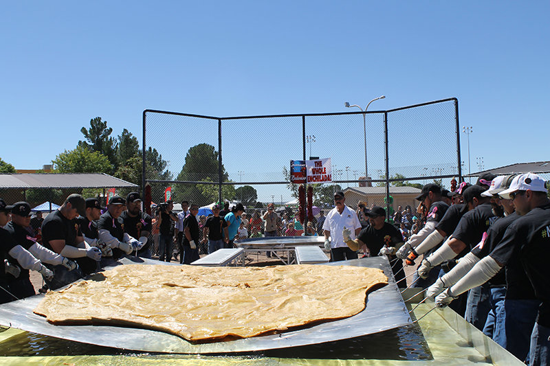 Roberto's team of volunteers move the 250-pound tortilla while creating the world's biggest enchilada at the Whole Enchilada Fiesta.