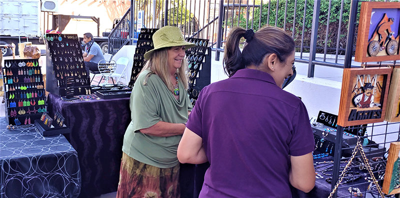 Marcella Huppke, left, with a customer at her Uniquely Chic Jewelry & Accessories booth at the Farmers and Crafts Market of Las Cruces.