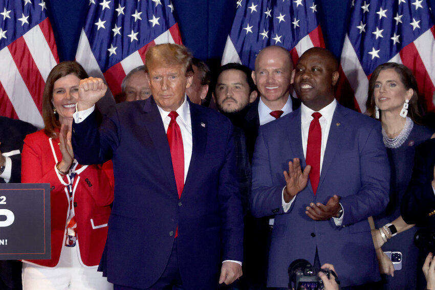COLUMBIA, SOUTH CAROLINA - FEBRUARY 24: Republican presidential candidate and former President Donald Trump gestures to supporters as Sen. Tim Scott (R-SC) looks on after Trump spoke during an election night watch party at the State Fairgrounds on February 24, 2024 in Columbia, South Carolina. Trump defeated opponent Nikki Haley in the South Carolina Republican primary. (Photo by Alex Wong/Getty Images)