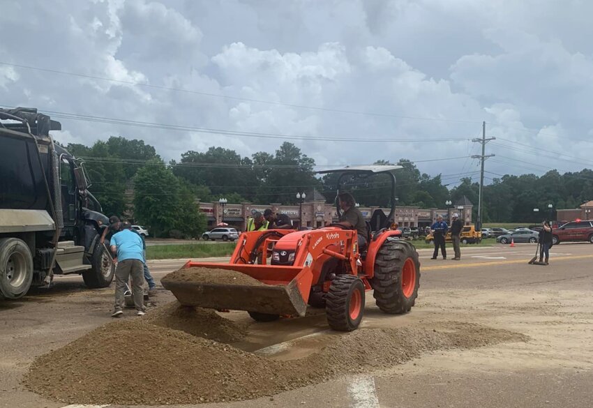 Public Works employees clean up gravel after a dump truck rolled over.