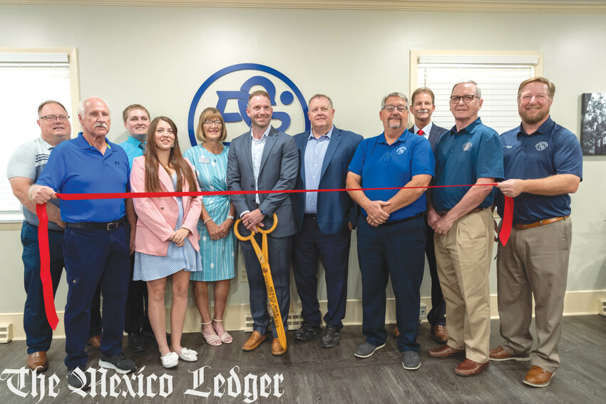 Derek Stuckenschneider, regional president of Peoples Savings Bank cuts the ribbon surrounded by staff and fellow executives here to show support (left to right) Kyle Williams, Bob Darr, Tanner Smith, Breanna Reeves, Nan Webber, Derek Stuckenschneider, Mark Laune, Todd Witthaus, Bart Toedtmann, Ron Carel and Don Meyer