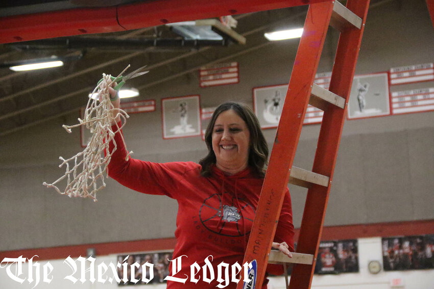 Mexico girls basketball head coach Makenzie Mudd holds up her team's home court net after cutting the rest of it down following Saturday's Class 4 District 8 championship victory over Kirksville. It was the program's first since 2006, when Mudd was a freshman.