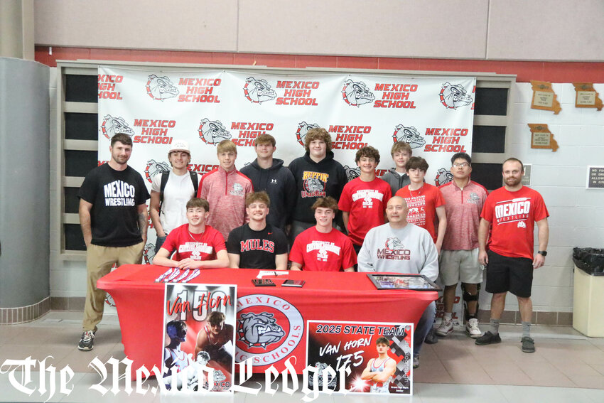 Mexico senior Grant Van Horn (sitting second from left) gathers with his teammates and coaches on Monday during his signing ceremony at the Mexico Sports Complex to wrestle for the University of Central Missouri in Warrensburg. Van Horn won a state championship and tied the program's all-time wins record this season.
