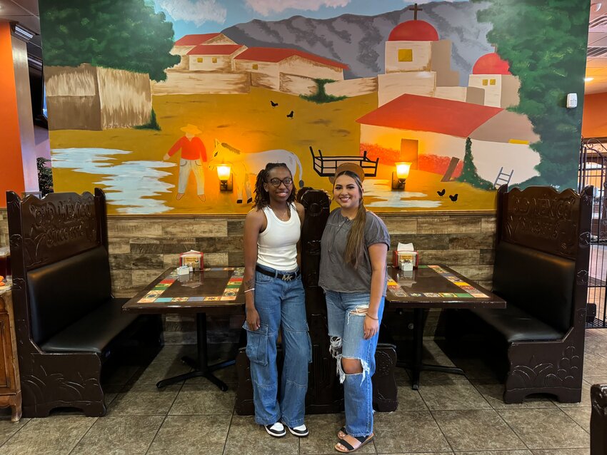 Lake Hall, left, and her best friend, Natalia Euyoque, right, pose in front of Hall's first ever mural painting at Old Mexico Restaurant.