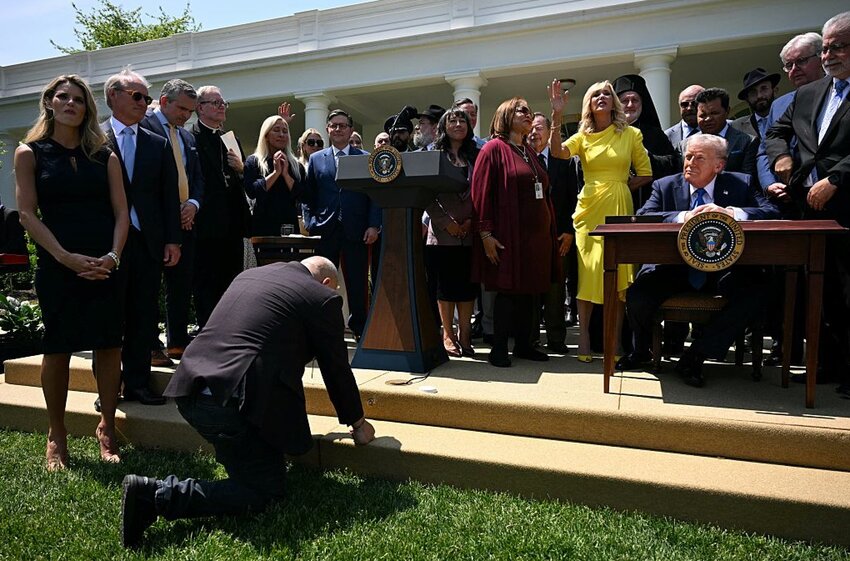 A man kneels in prayer in front of US President Donald Trump during a National Day of Prayer event in the Rose Garden of the White House in Washington, DC, on May 1, 2025.