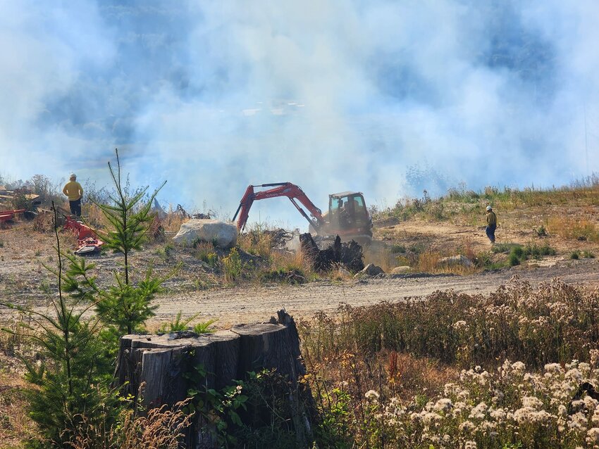 Fire fighter personnel utilize a backhoe during the effort to shut down a brush fire that stated late Tuesday afternoon. The blaze was contained after burning round three acres.