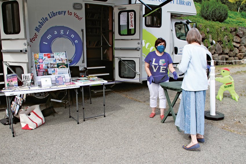 Jefferson County Library bookmobile staffer Kristin Hill assists a patron last week at the Port Ludlow Village Market stop.