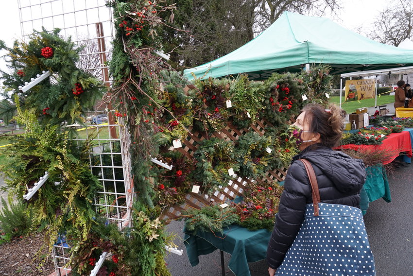 A shopper examines holiday wreaths for sale at the Port Townsend Farmers Market Saturday.