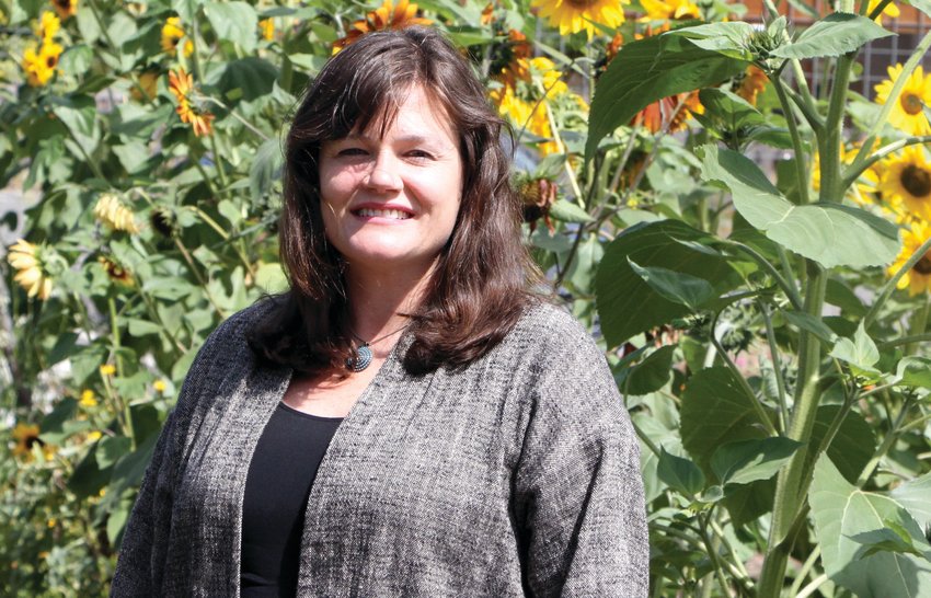 Rosenbury poses in front of the sunflowers at Salish Coast Elementary School&rsquo;s teaching garden, an integral setting for her place-based learning program.