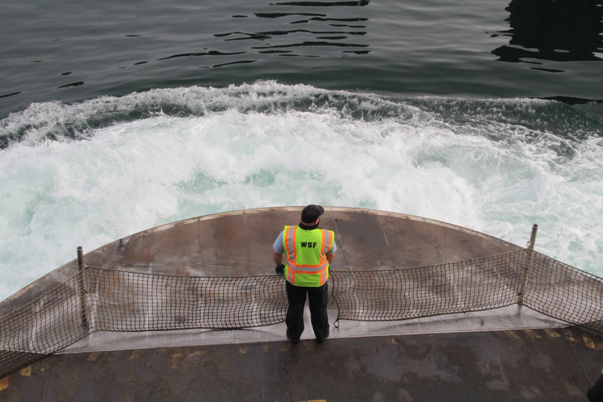 A crew member aboard the M/V Kennewick stands ready to take down the deck netting as the vessel approaches the ferry terminal in Port Townsend.
