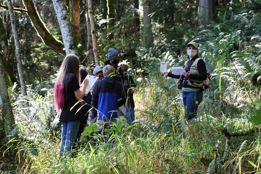 Quilcene students jot down notes as Jefferson Land Trust&rsquo;s Snow Creek Forest Preserve manager Carrie Clendaniel lends a hand for student fieldwork education.