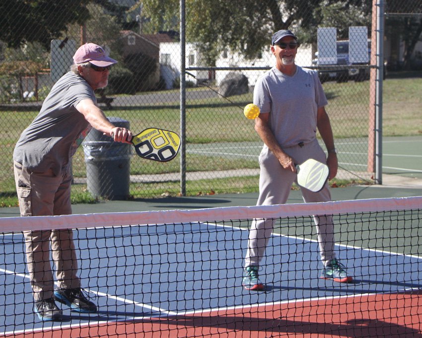 Local resident Hal Leskinen volleys a pickleball ball over the net back to Tom Young.