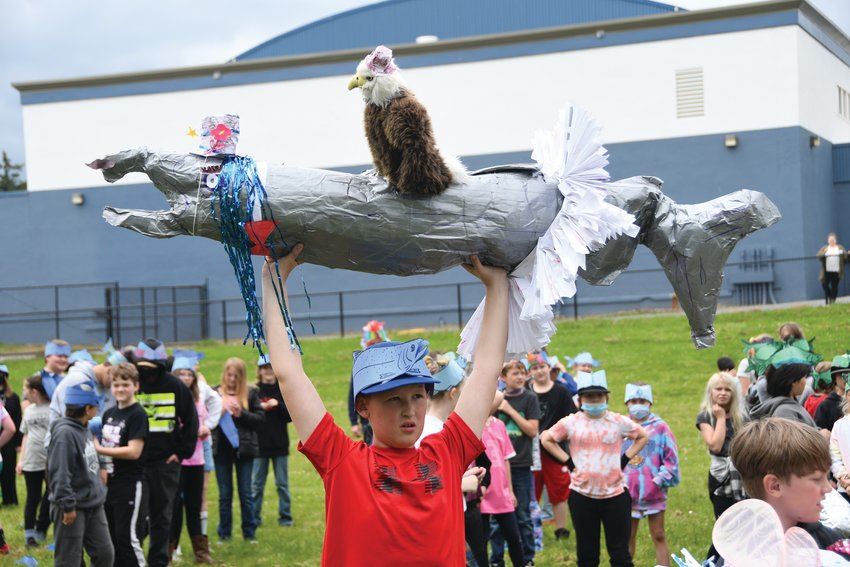 Fifth-grader Brayden Tuttle holds up his team&rsquo;s salmon avatar, decorated with an eagle and a tutu.