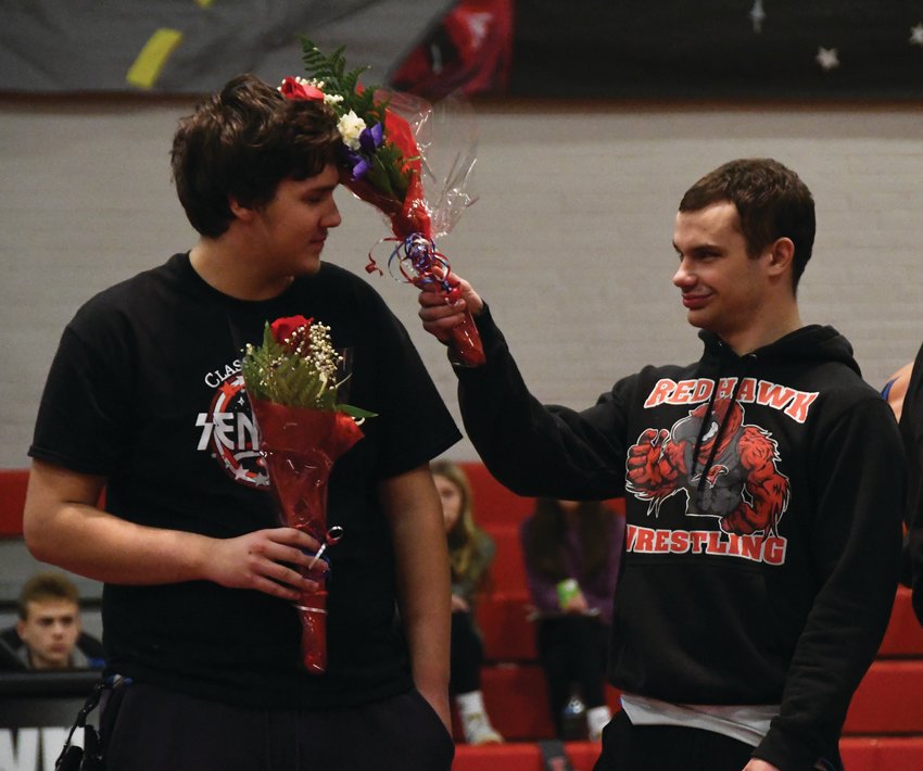 EJ senior Ike Banks gives his teammate a friendly flower &ldquo;bonk&rdquo; during the wrestling program&rsquo;s senior presentation before the varsity matchups.