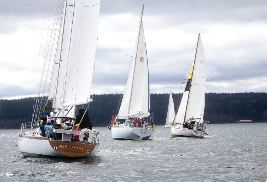 Sailors from last year&rsquo;s Shipwrights&rsquo; Regatta glide toward Boat Haven Marina through Port Townsend Bay, with the local landscape behind them.