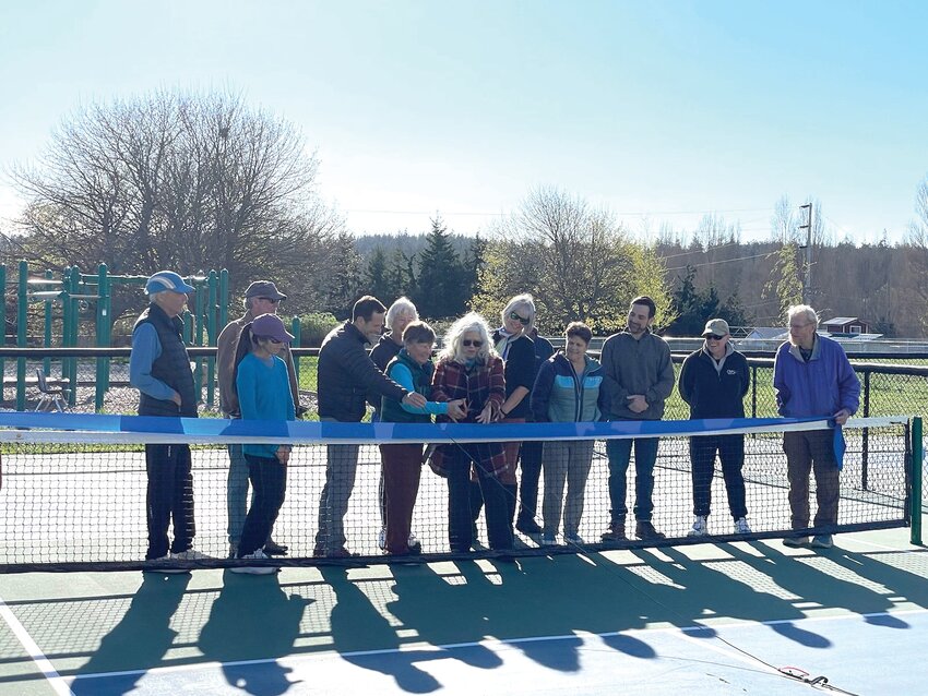 Port Townsend Pickleball Club President Lynn Pierle and city Councilmember Monica MickHager cut the ribbon at the Mountain View Commons; city representatives and club board members watch from both sides.