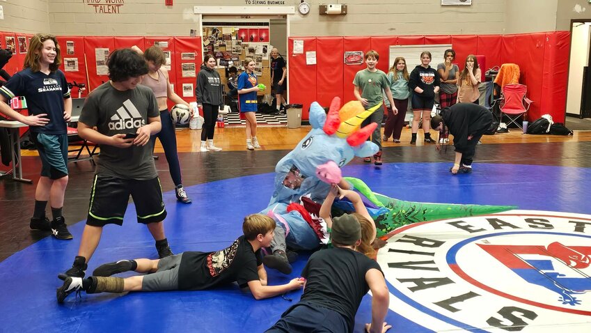 Two East Jefferson Rivals wrestlers attempt to grapple while wearing dinosaur costumes at the combined joint practice with South Whidbey. Chase Gardner and Sam Raymond appear to be locked in a &ldquo;Jurassic Park&rdquo; battle on the mat. Cheering them on, clockwise from far left: East Jefferson middle school wrestlers Piper Hawkin, Aleutian Durst, Dane Moore, Gracee Liske, Leighton Dunn, Daltry Lammers and Trafford Henery. Aiden Glenn and Boston Huntingford also assist the match as volunteer refs. Some kids chose to wear costumes for the event. Courtesy photo