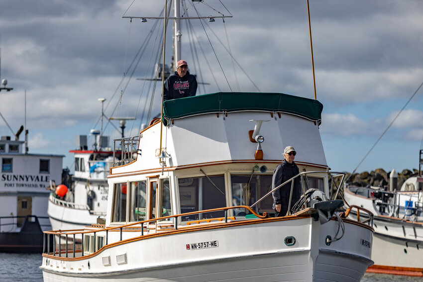 Scott Wilson stands at the helm of his boat at the Boat Haven in Port Townsend, while his spouse, Jennnifer Wilson stands at the front of the vessel.