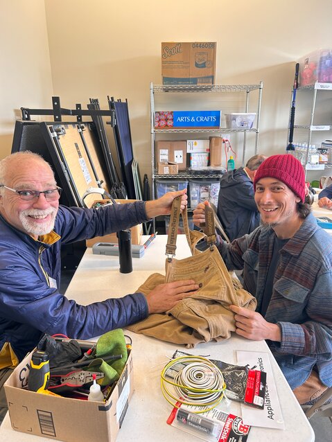 Volunteer Eric McRae, left, and a satisfied repair event participant managed to repair a set of overalls with a damaged clip.  Photo courtesy of Mandi Johnson