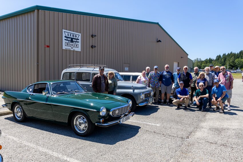 The Port Townsend Aero Museum, at the Jefferson County International Airport, was visited by members of the Puget Sound Chapter of the Volvo Sports America Club, including Michael and Marilyn Deskins, at the dark green 1967 1800S Volvo; plus Holly Tartar, Dick Libby, Ingvar Carlson, Jim Washington, Oliver Henry, Dave Smith, Phill Brodt, Sherly and Barry Mattausch, Charlie and Florence Mayne, and Walt Tarter, standing; as well as Dale Ridings, Vince Hoss and Paul Ballew, kneeling.