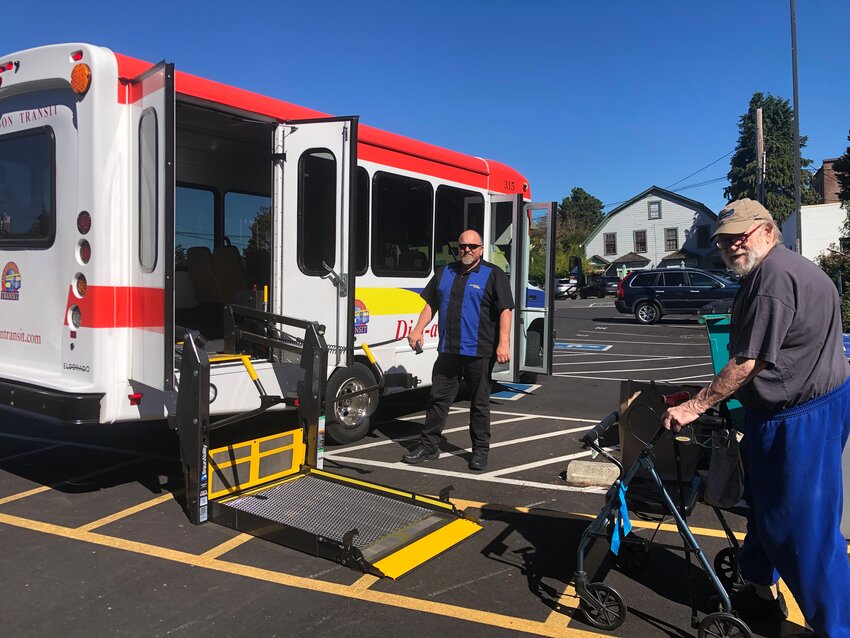 Marshall New boards the Jefferson Transit Authority Dial-A-Ride bus with the help of bus driver Geno Barlow. Photo by James Robinson