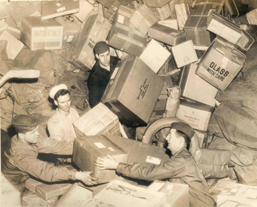 U.S. troops almost buried by parcels do their best to handle that year&rsquo;s holiday mail during World War II.