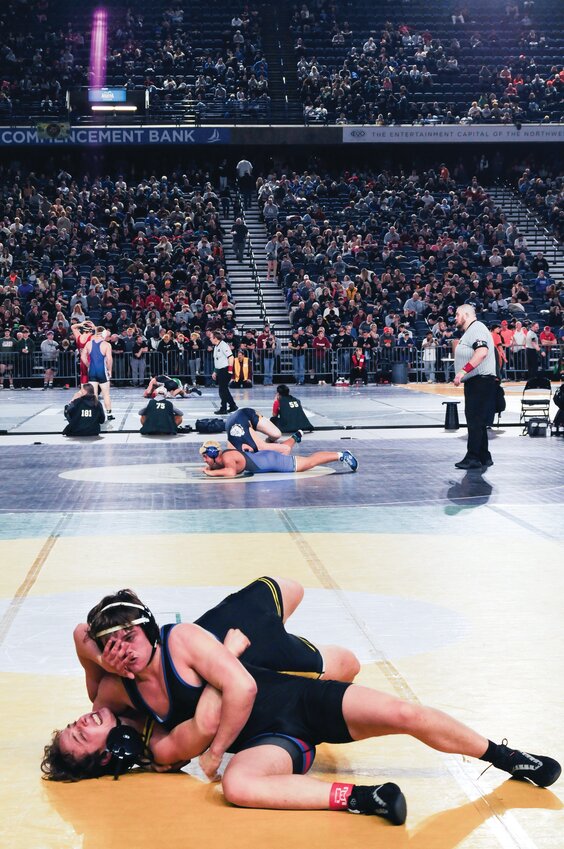 Silas Klontz tightens his grip, locking his opponent in a headlock. He showcases his strength on the mat as the crowd watches in anticipation. He secures a win.