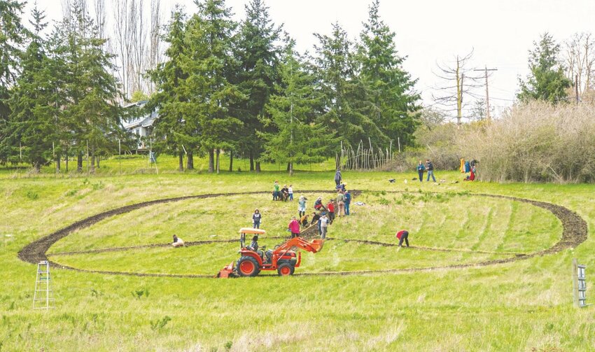 Volunteers weed an overgrown peace sign April 16, 2018, on property owned by the Port Townsend Preservation Alliance. Property owner Celine Santiago said a peace sign of some sort will be incorporated into plans for the land.