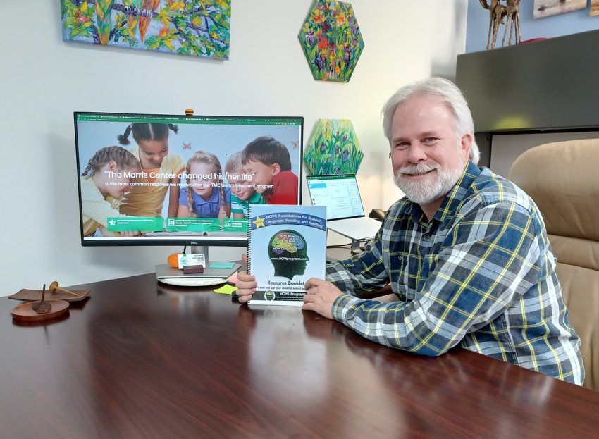 Dr. Tim Conway is seen at his desk with his resource booklet for &ldquo;NOW! Foundations for Speech, Language, Reading and Spelling.&rdquo;
