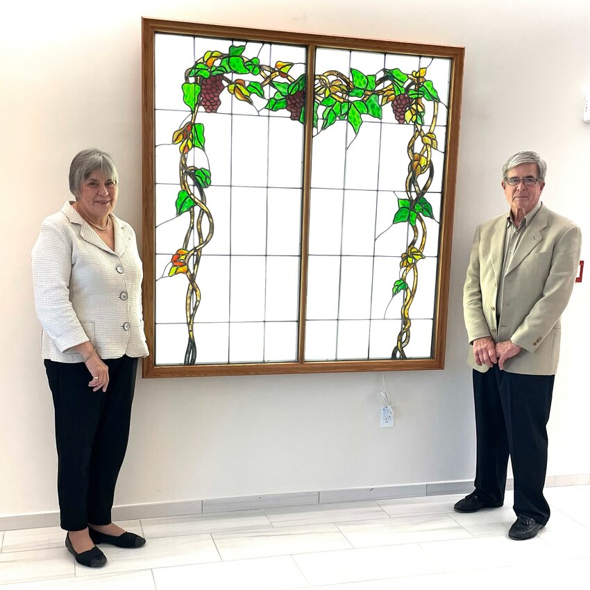 Walter and Sally Suslak stand next to the restored stained-glass window which is now located at Ascension St. Vincent&rsquo;s newest campus.