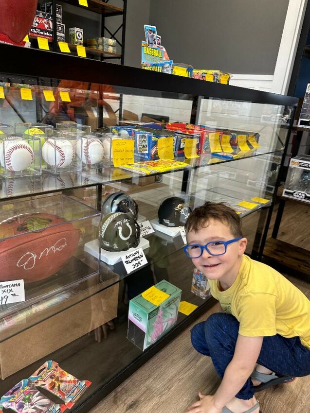 Six-year-old Finn Mailes admires autographed football mini-helmets and a signed Joe Montana football in the display case at the newly opened Ponte Vedra Beach Cards and Comics in the Winn-Dixie Shopping Center by Don's Barber Shop and Dunkin Donuts.