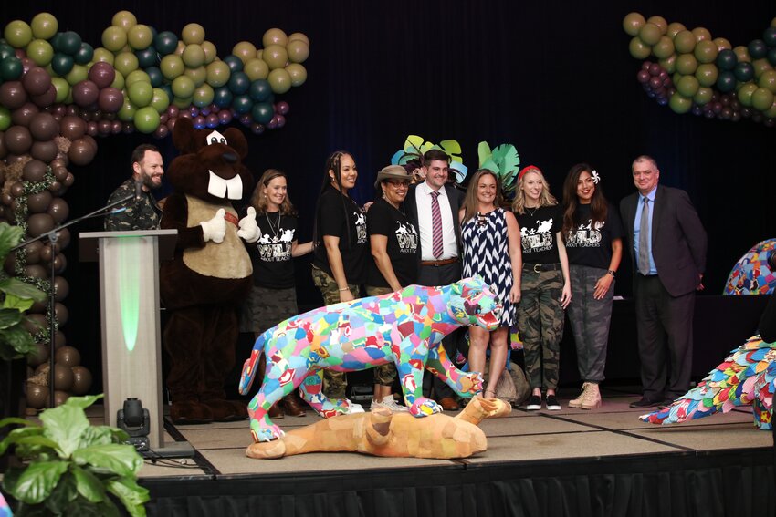 INK! Teacher of the Year Celebration 2023 with Tracy Clauson St. Johns County District Teacher of the Year 2023 on stage with the emcees and Ocean Sole sculptures.