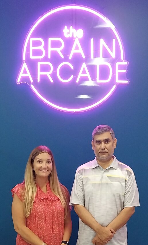 Unlockt Program Director Eva Luther and founder Raghu Misra stand below the Brain Arcade sign.