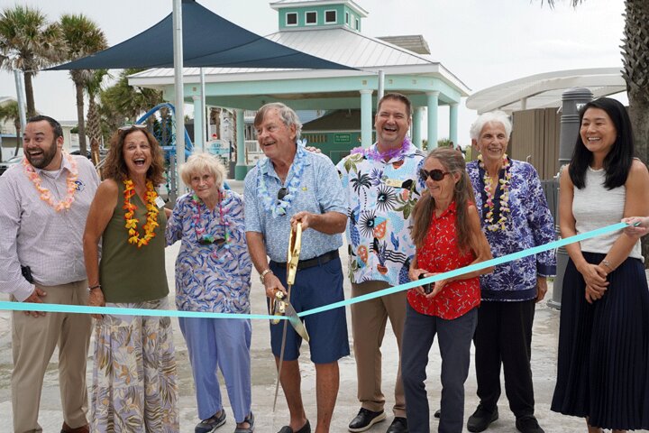 Commissioner Henry Dean cuts the ribbon on the completed Vilano Beach Oceanfront Park project, while stakeholders gather round.