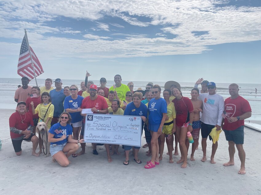 Coldwell Banker Realtor Savannah Elam and Coldwell Banker CBV Cares Co-Chair Carole Bayer present a check to Special Olympics Coach Jeff Burnette, assisted by Coldwell CBV Cares Co-Chair Nancy Hammond and Coldwell Banker Broker Manager Michele DeLiberto as Special Olympics athletes and coaches gather round.