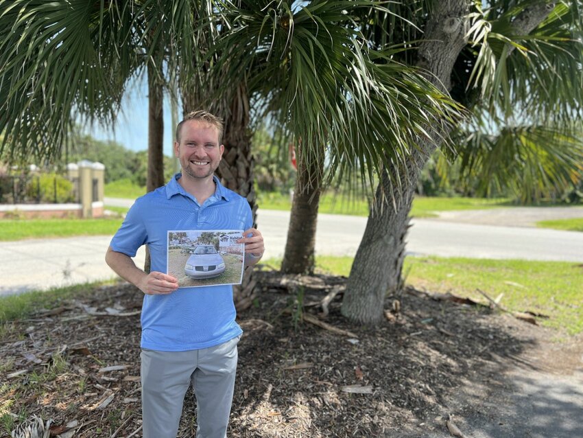 Dr. Caleb Bunting with a photo of the car he donated to the Habitat for Humanity&rsquo;s Cars for Homes program.