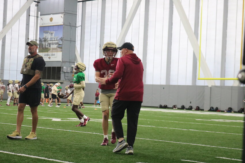 Nease alum and Florida State defensive back Cade Papineau receives instruction from a coach during practice.