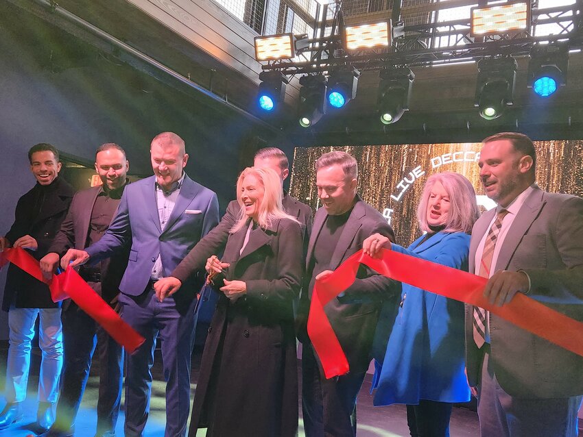 Jacksonville Mayor Donna Deegan cuts the ribbon during Decca Live&rsquo;s opening ceremony while surrounded by venue owners and city representatives on stage.