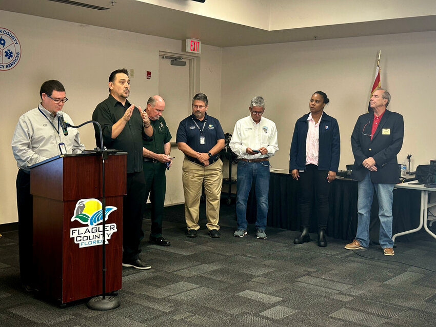 L-R: Flagler County Emergency Management Director Jonathan Lord, a sign language interpreter, Sheriff Rick Staly, County Commission Chair Andy Dance, Flagler Beach City Commission Chair Scott Spradley, Superintendent LaShakia Moore, and Palm Coast Mayor David Alfin.