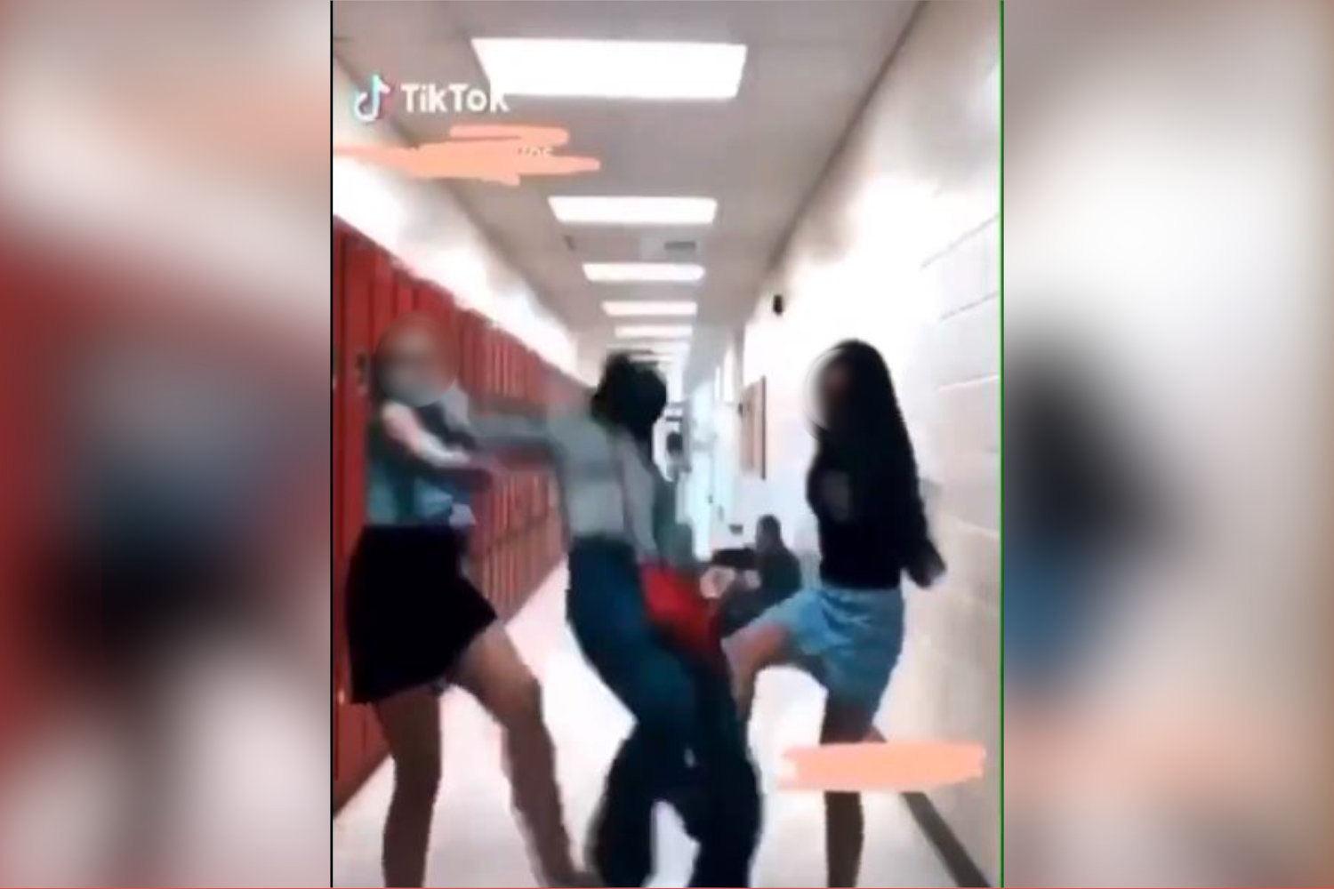A screencap of the video showing two girls tripping another student on TikTok