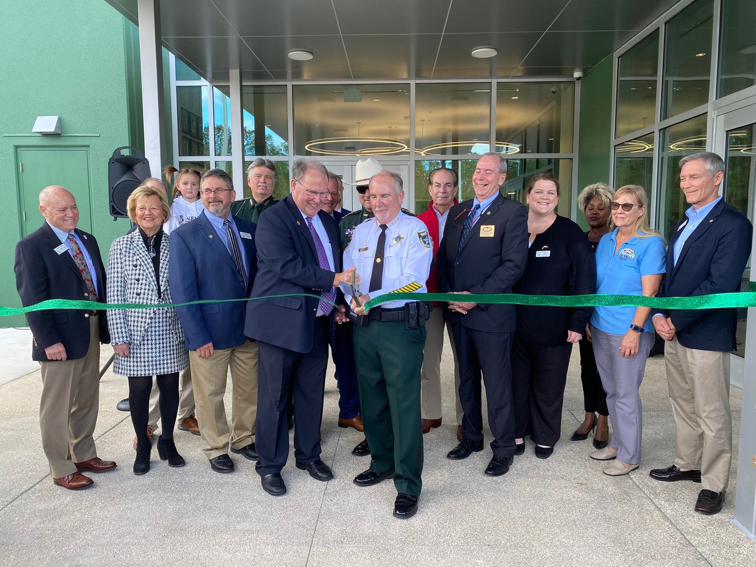 A line of elected officials and FCSO staff kick off a new era. County Commission Chair Greg Hansen and Sheriff Rick Staly are at the forefront, cutting the ribbon.