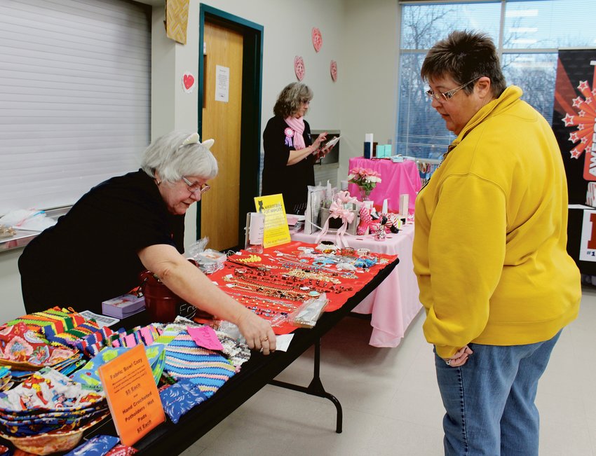 Sarah Bailey shows her homemade jewelry and fabric potholders and hot pads to Michele Stanfield at Shop Local Night on Feb. 6.